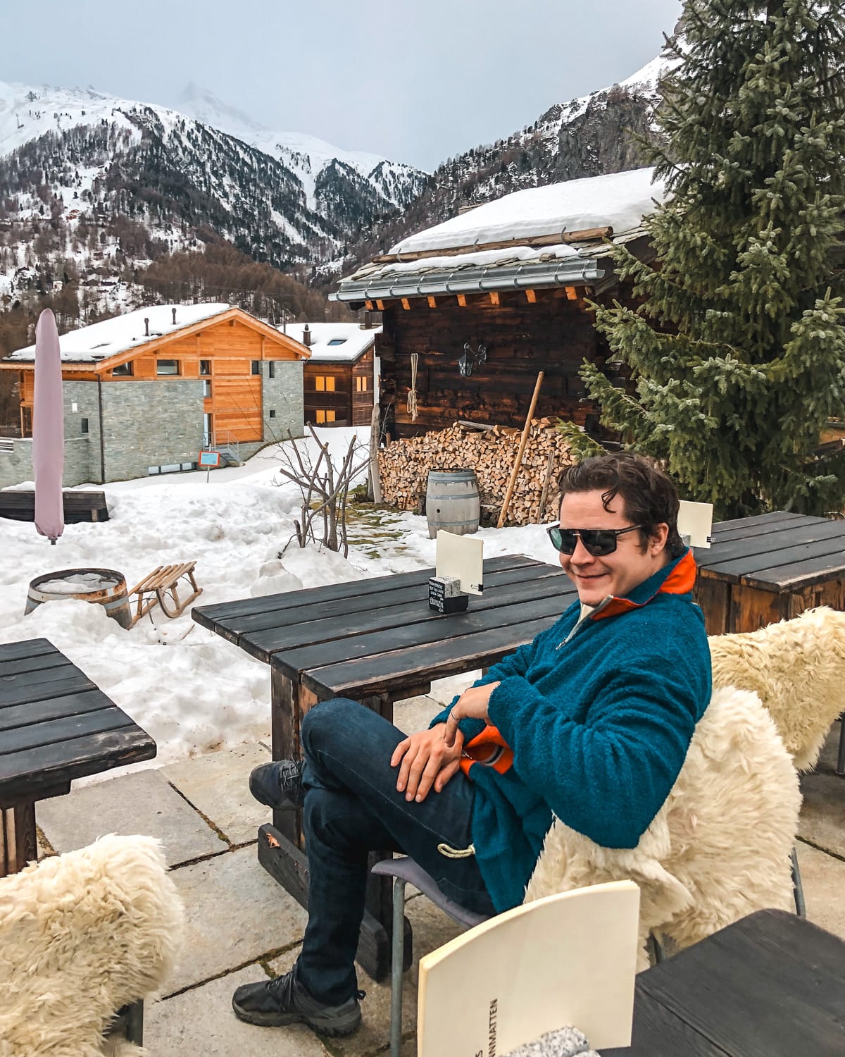 Ari sitting on lambskins outside at a restaurant in Zermatt