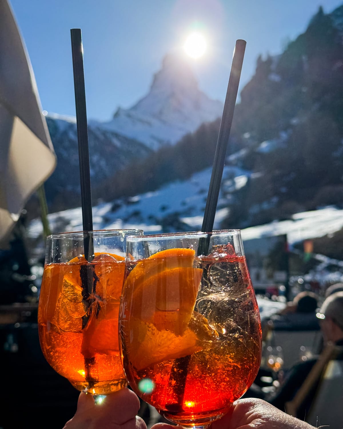 Two Aperol Spritz clinking with a view of the Matterhorn