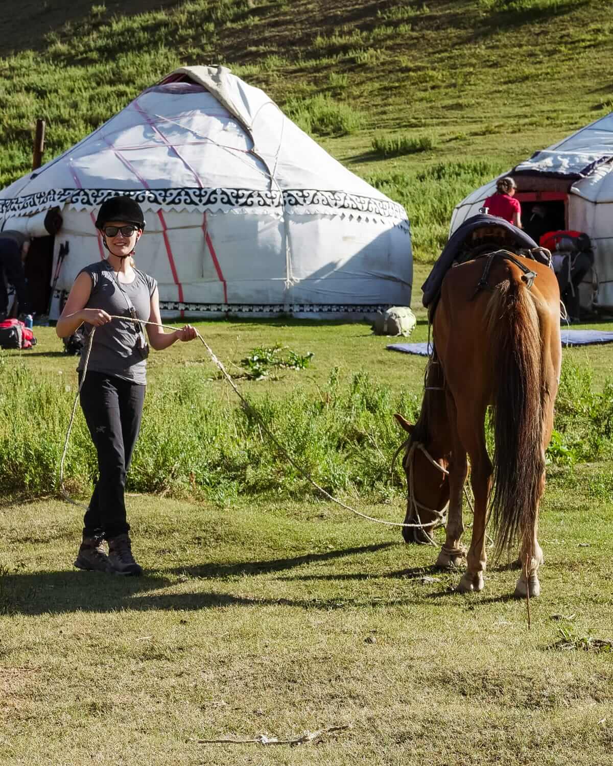 Cec holding a horse's lead in front of traditional yurts.