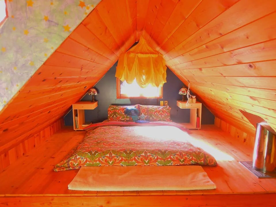 A bed sits in the loft of an A-frame cabin at Eagle's Nest Retreat