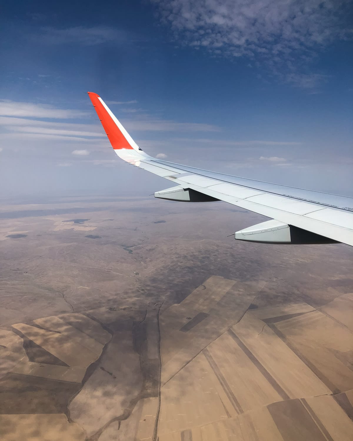 View from an airplane window flying over the dry landscapes and farmland of Kyrgyzstan.