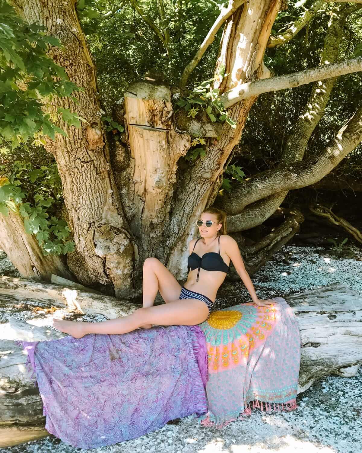 Cec relaxing on driftwood under trees at the peaceful Montague Harbour Beach.