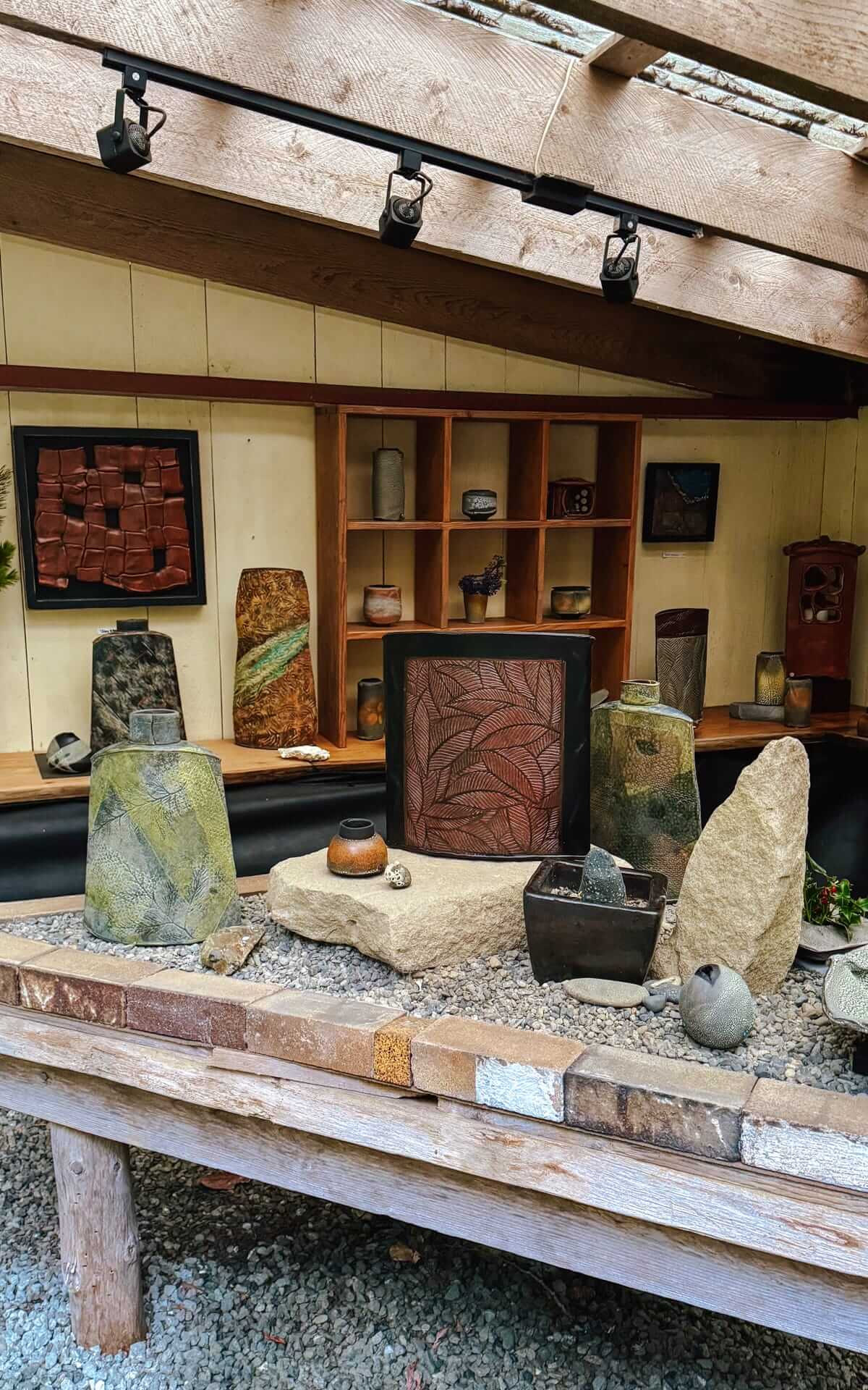 Outdoor gallery showcasing ceramic artwork, stone textures, and handcrafted pottery on display.