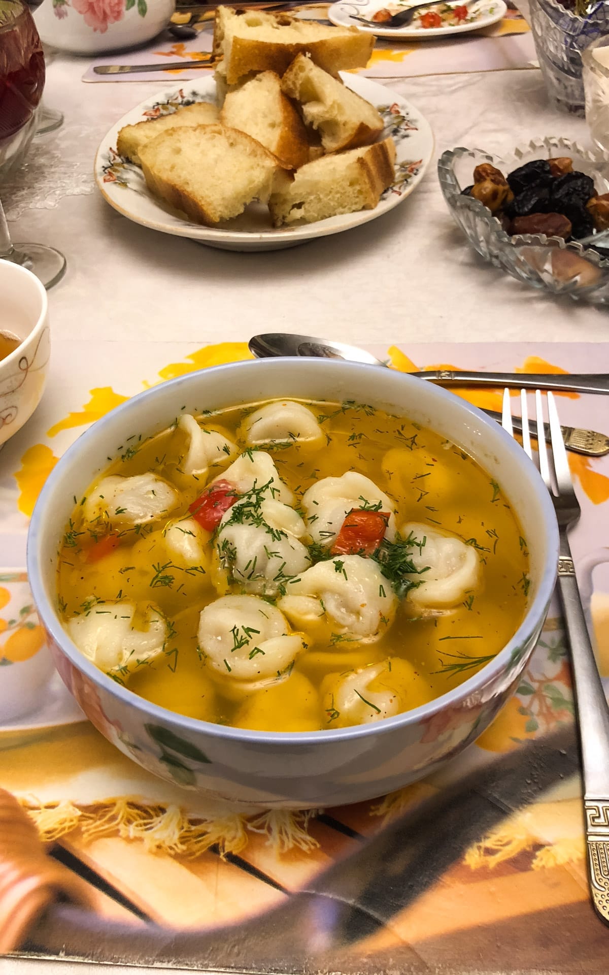 Traditional Kyrgyz meal featuring a bowl of pelmeni soup on a dinner table.