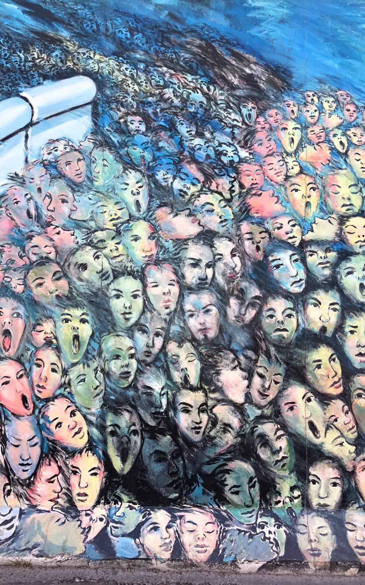 A mural at the East Side Gallery shows expressive faces merging together.