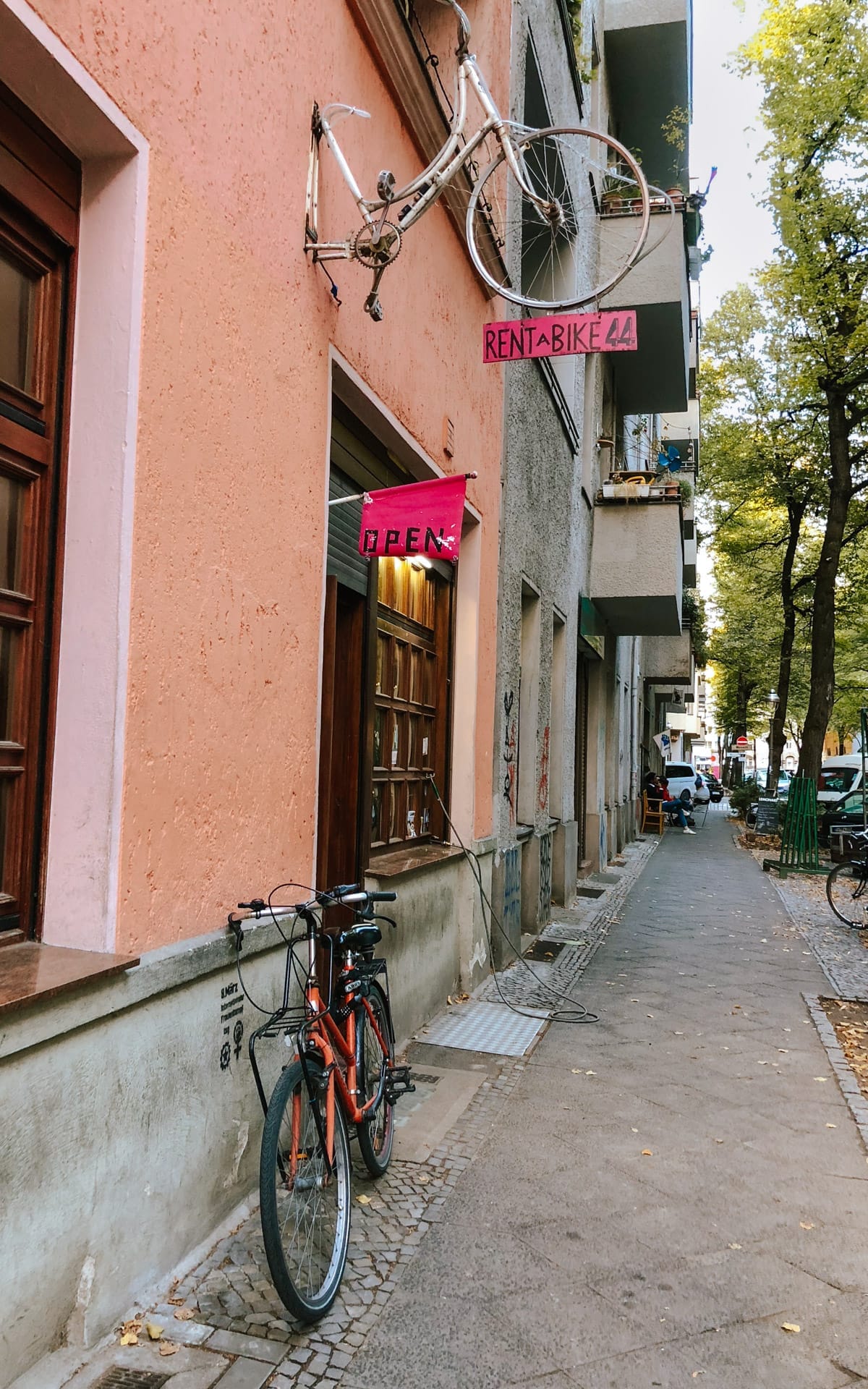 A pink-walled Berlin bike shop with a vintage bicycle mounted above the entrance and a bright pink "Rent a Bike" sign.